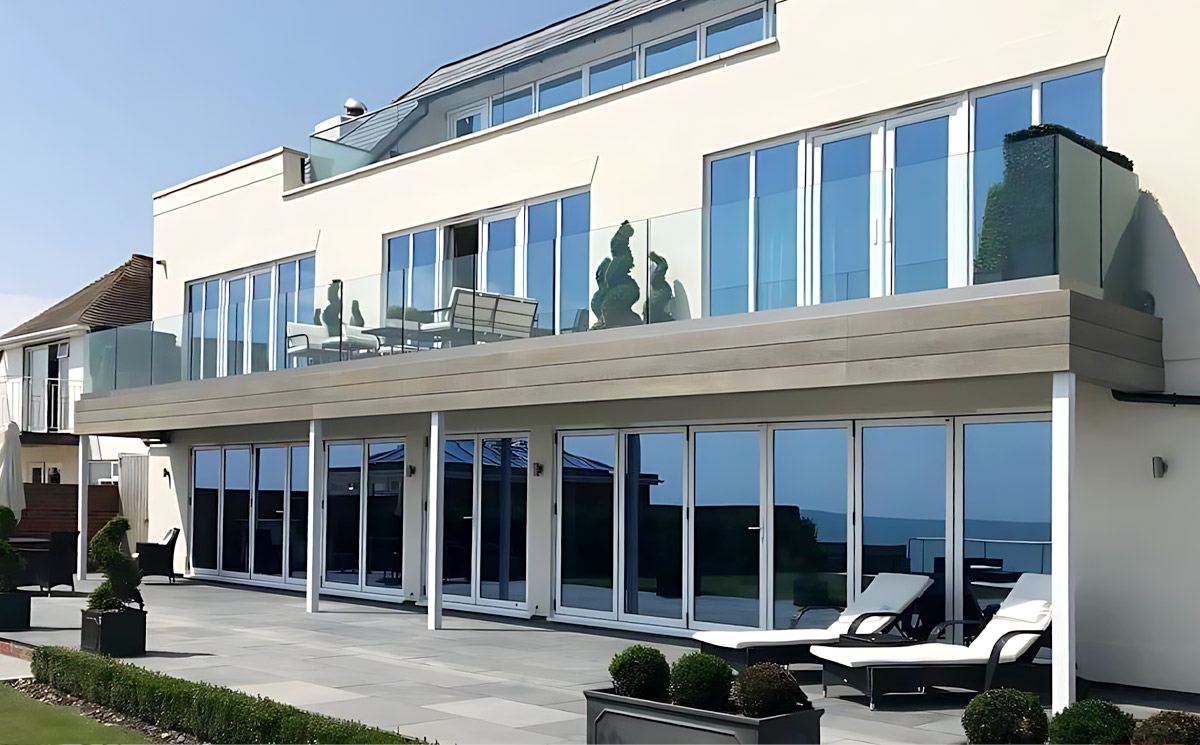 A multi-story modern seaside villa featuring custom aluminum folding doors across all patio and balcony levels A multi-story modern seaside villa featuring custom aluminum folding doors across all patio and balcony levels