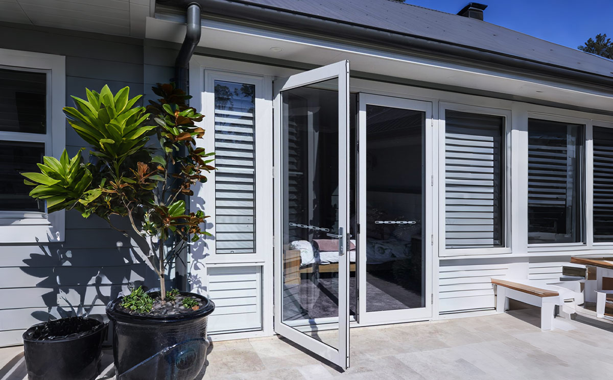 Exterior outswing French patio door open onto a backyard deck Exterior outswing French patio door open onto a backyard deck