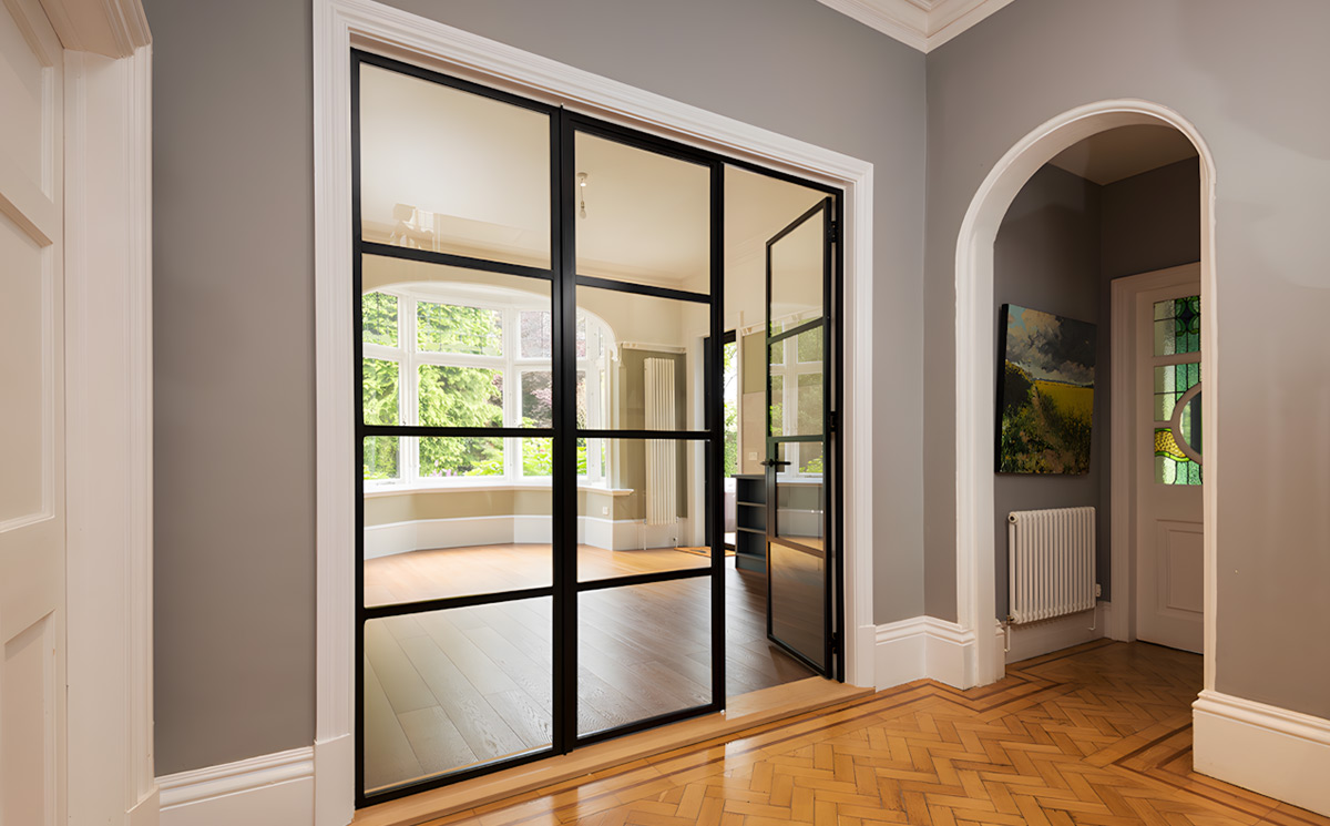 Modern interior French room divider doors with black slim frames and glass grids dividing living room and hallway Modern interior French room divider doors with black slim frames and glass grids dividing living room and hallway