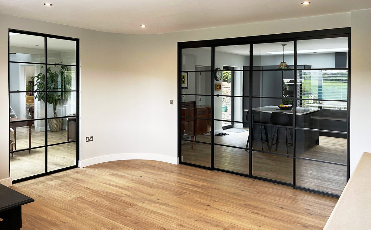 Steel-look French doors double configuration with thin black grid frames used as an interior glass wall divider Steel-look French doors double configuration with thin black grid frames used as an interior glass wall divider