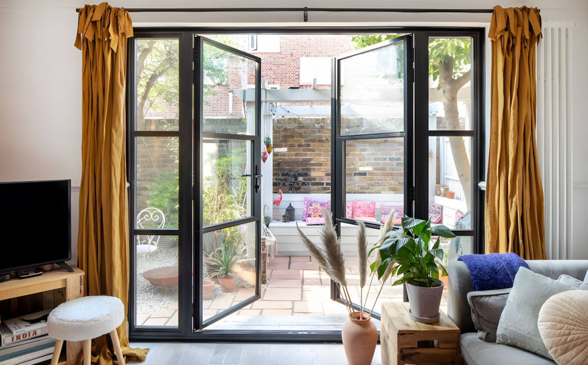 Modern minimalist black narrow frame glass doors opening to outdoor courtyard patio Modern minimalist black narrow frame glass doors opening to outdoor courtyard patio