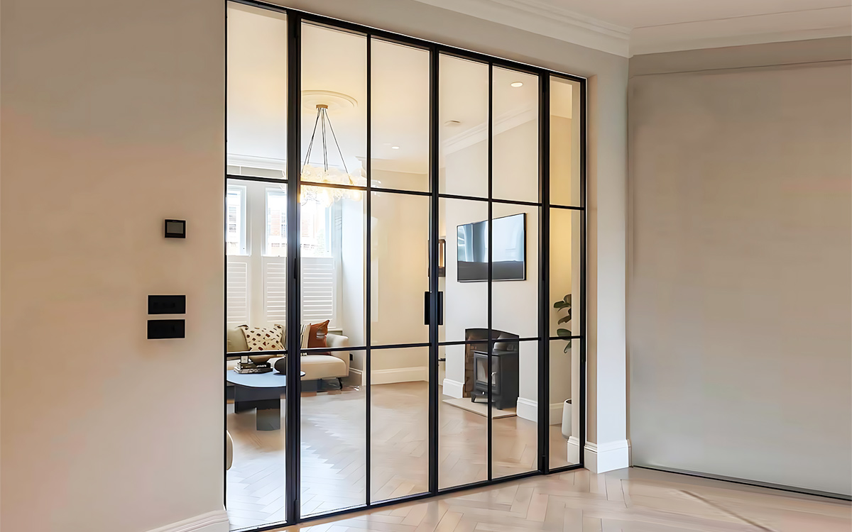 Black metal grid entry doors with transom and sidelights framing a warm villa hallway entrance Black metal grid entry doors with transom and sidelights framing a warm villa hallway entrance