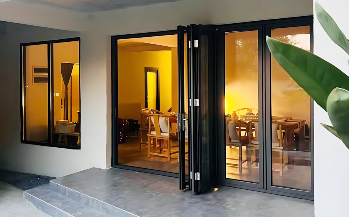 Aluminum glass folding doors open view connecting modern villa interior dining space to outdoor terrace Aluminum glass folding doors open view connecting modern villa interior dining space to outdoor terrace