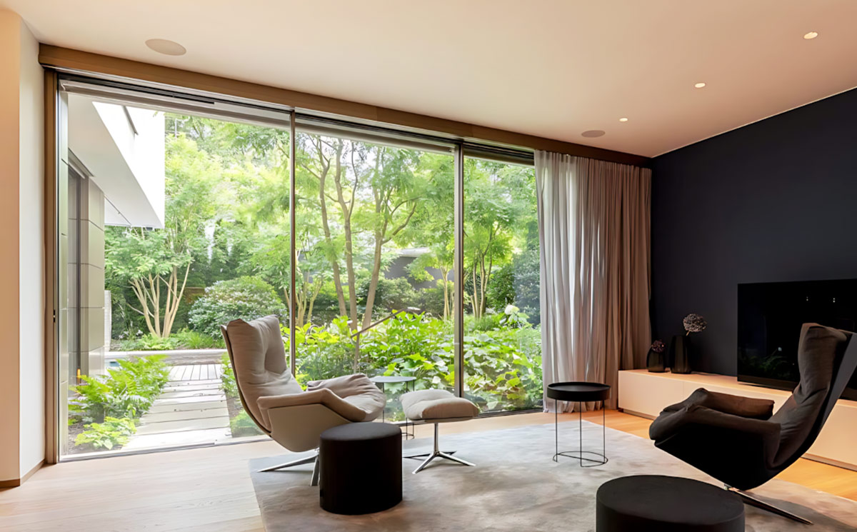 Modern living room interior with ultra slim sliding door providing uninterrupted green garden view Modern living room interior with ultra slim sliding door providing uninterrupted green garden view