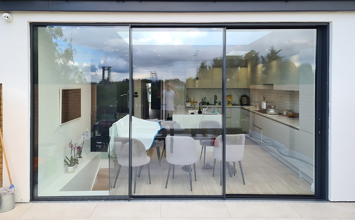 Aluminum sliding glass door connecting contemporary indoor kitchen and dining area to outdoor patio Aluminum sliding glass door connecting contemporary indoor kitchen and dining area to outdoor patio